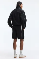 Short deportivo negro con bandas laterales blancas, cintura elástica con cordón ajustable blanco y bolsillos laterales.