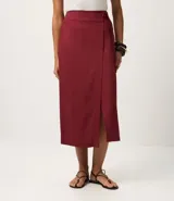Pollera midi color bordó, estilo sobre, con traspase delantero alargado y lazo lateral con tiras finas. Posee cintura estructurada, caída recta y encaje discreto formado por la superposición de las capas. Confeccionada en viscolino (viscosa y lino).