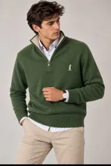 Buzo de punto fino color verde con cuello alto y medio cierre frontal, manga larga y puños acanalados. Cuenta con un pequeño bordado en el pecho.