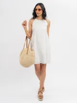 Vestido corto blanco de broderie, sin mangas y con escote halter de corte evasé.