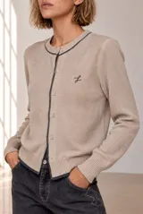Cardigan de punto azul con ribetes en contraste negro, cuello redondo, cierre frontal con botones y bordado pequeño en el pecho.