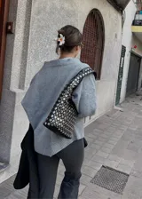 Cartera negra tipo hobo con tachas plateadas de diferentes tamaños.