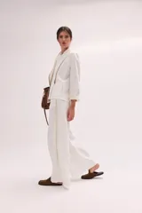 Chaqueta de lino lavado color blanco, con cuello mao, cierre metálico diagonal y detalles en contratono.