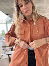 Sobrecamisa color terracota de pana con cuello camisero, cierre frontal con botones, dos bolsillos con solapa en el pecho y mangas largas con puños abotonados.