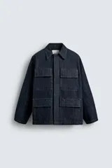 Chaqueta de denim de algodón en color azul oscuro, con corte relajado, cuello solapa, manga larga y cuatro bolsillos frontales con solapa. Presenta cierre frontal oculto por solapa.