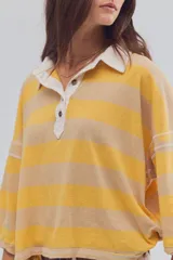 Remera tipo polo de algodón, de calce oversize, con diseño a rayas en tonos azul y celeste, cuello clásico blanco, botonadura corta, hombros caídos y mangas cortas.