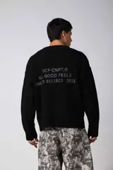 Sweater de punto acanalado color marrón, con cuello redondo, mangas largas y calce relajado. Presenta una estampa pequeña en el centro del pecho.