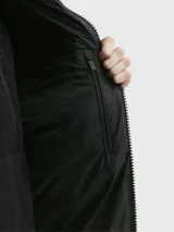 Campera corta acolchada de Moncler, modelo Alrai, en color gris oscuro. Presenta diseño de celdas horizontales, cierre frontal completo, capucha integrada y puños con aberturas para los pulgares.
