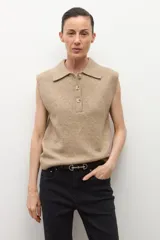 Chaleco de punto color tostado melange, con cuello polo y abotonadura frontal de tres botones. Sin mangas.