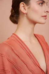 Aritos colgantes dorados con piedra ovalada de color rosa.