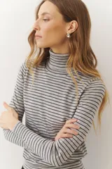 Rompeviento color beige con rayas horizontales finas en marrón, cuello alto y mangas largas.