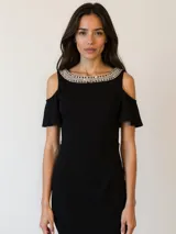 Vestido corto negro con hombros descubiertos y detalle de pedrería en el cuello.