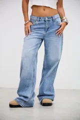 Jean de tiro medio en color celeste, con corte recto y holgado. Presenta detalle de tachas metálicas pequeñas a lo largo de las costuras laterales y en la zona de los bolsillos delanteros.