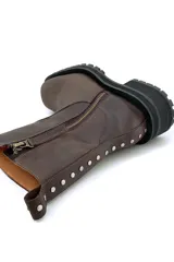 Bota de cuero color chocolate, con caña media, cierre lateral y tachas decorativas en la parte trasera.