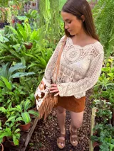 Bandolera de cuero con estampado animal print de vaca en tonos marrón y blanco, con flecos de cuero marrón en los laterales. Tiene correa larga de cuero marrón regulable y asa de mano con forma ovalada.