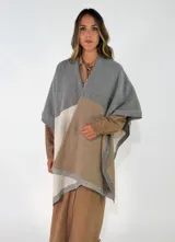 Ruana de tejido de punto con diseño de bloques de color en tonos gris, beige y crudo, con terminaciones acanaladas en los bordes.