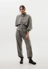 Pantalón de vestir de corte holgado, con pinzas frontales y detalle de solapas decorativas sobre los bolsillos laterales. Presenta cintura de altura media y bolsillos traseros tipo ojal.