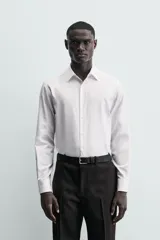 Camisa de corte slim fit confeccionada en tejido de algodón. Presenta cuello italiano, manga larga con puños abotonados y cierre frontal mediante botonadura clásica.