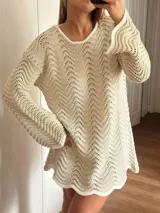 Vestido corto de tejido calado con patrón de ondas, confeccionado en algodón y lurex. Presenta mangas largas, cuello redondo y diseño holgado.