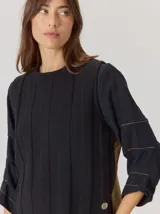 Chaleco de paño con diseño bicolor, frente en color negro y espalda en color marrón con textura de espiga. Presenta un maxi bordado de hoja en la parte posterior y detalles de tejido en los bordes.