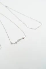 Set de cuatro pulseras de cadena fina en color plateado con diferentes diseños: una con dijes de corazones, una con un dije de corazón grande, una con dijes circulares pequeños y una con eslabones en forma de corazón.