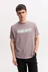 Remera de manga corta color gris topo, con cuello redondo y estampa frontal de estilo urbano con texto en tono claro.