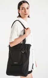 Bolso tipo tote bag de microfibra negra, con correas de hombro y cordón ajustable con tanca. Posee un bolsillo exterior con velcro y un bolsillo interior con cierre.