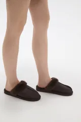 Pantuflas cerradas color marrón con ribetes de piel sintética en la abertura y suela plana.