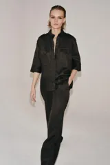 Pantalón flare de tiro medio confeccionado en lino color marrón. Cuenta con cintura con trabillas, bolsillos delanteros, perneras de corte evasé y cierre frontal con cremallera y botón.