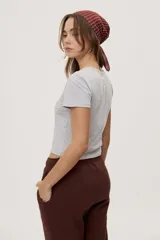 Remera blanca de manga corta, con estampa frontal de un pato de hule con turbante y labios pintados, acompañada de la frase "In all else fails, denial".