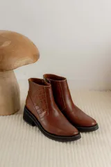 Bota corta de cuero marrón con panel trasero de gamuza en tono más oscuro, suela de goma negra y taco cuadrado bajo.