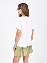 Remera blanca de manga corta con cuello redondo y un estampado frontal de un jarrón azul a rayas con flores rosadas.