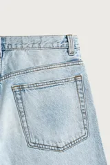 Bermuda de denim de algodón con efecto lavado desgastado en tonos marrones y azules. Tiene tiro medio, diseño de cinco bolsillos, pierna recta de corte holgado y bajo con acabado irregular. Cuenta con cierre frontal de cremallera y botón metálico.