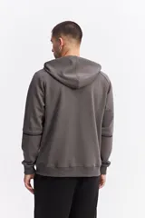 Campera con capucha y cierre frontal, color beige, con detalles de costuras y cierres en negro. Presenta mangas largas con puños acanalados y logo pequeño en el pecho.