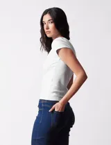 Remera blanca de tejido acanalado, marca Cyrus, con escote a la base y manga corta.