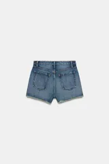Shorts de jean de algodón, tiro alto, color azul claro desgastado. Presenta cinco bolsillos, cierre frontal con botón metálico y cremallera, y bajo desflecado con vuelta.