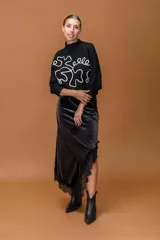 Falda midi confeccionada en terciopelo negro, con corte irregular y terminación de encaje en el ruedo.