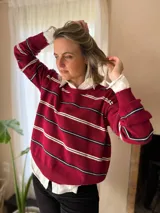 Sweater de punto en color bordó con diseño de rayas horizontales en blanco y negro. Presenta escote redondo a la base, mangas largas con puños acanalados y un calce holgado.