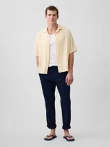 Camisa de manga corta color beige claro, con cuello cubano y cierre frontal de botones.