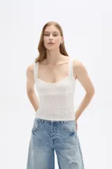 Top sin mangas confeccionado en algodón con diseño de broderie, corte al cuerpo y escote redondo con detalle de puntilla en los bordes.