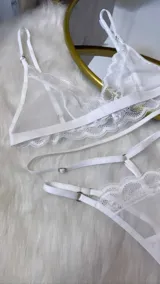 Set de lencería de cuatro piezas compuesto por bralette de encaje y microtul, tanga regulable, portaligas y ligas. Diseño con transparencias y detalles de encaje.