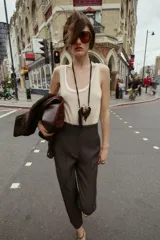 Pantalón de tiro alto color beige, con detalle de costuras marcadas en el delantero y la espalda. Incluye bolsillos delanteros de vivo y cierre frontal con cremallera, botón interior y gancho metálico.