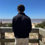 Camisa de manga larga color beige claro, con textura de lino arrugado y corte boxy. Presenta cuello camisero y cierre frontal de botones.