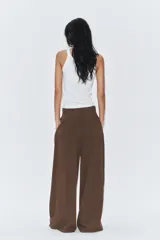 Pantalón de tiro medio color marrón, con pinzas en el delantero, perneras anchas de corte recto y trabillas para cinturón. Cuenta con bolsillos laterales y traseros, y cierre frontal con cremallera y botón.