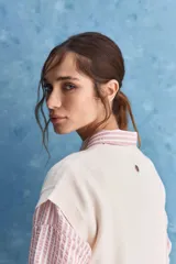 Chaleco de tejido de punto color beige claro, con cuello redondo y diseño de líneas limpias con hombros caídos y terminaciones acanaladas.