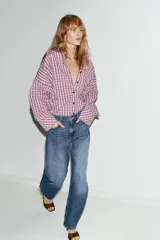 Jeans de tiro alto con diseño barrel, caracterizado por una silueta curvada y holgada en la zona de los muslos y rodillas, estrechándose hacia el tobillo. Cuenta con cinco bolsillos y cierre frontal con cremallera y botón.