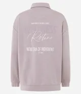 Buzo deportivo de corte oversized color lila, con cuello polo y cierre frontal con botones a presión. Presenta mangas largas con puños ajustados y una estampa bordada en el pecho. Confeccionado en una mezcla de poliéster, modal y elastano.