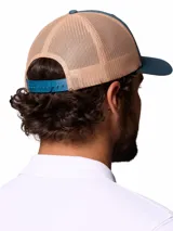 Gorro trucker Columbia de color verde azulado y beige, con paneles de malla trasera y un parche frontal estampado con un oso y la marca.