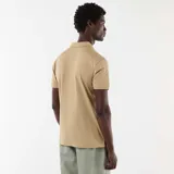 Remera polo color beige de manga corta, confeccionada en tejido texturizado tipo nido de abeja, con cuello camisero y cierre frontal de botones.
