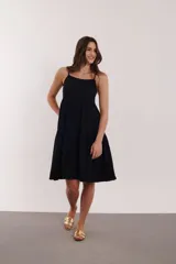 Vestido corto negro con breteles finos y falda escalonada.